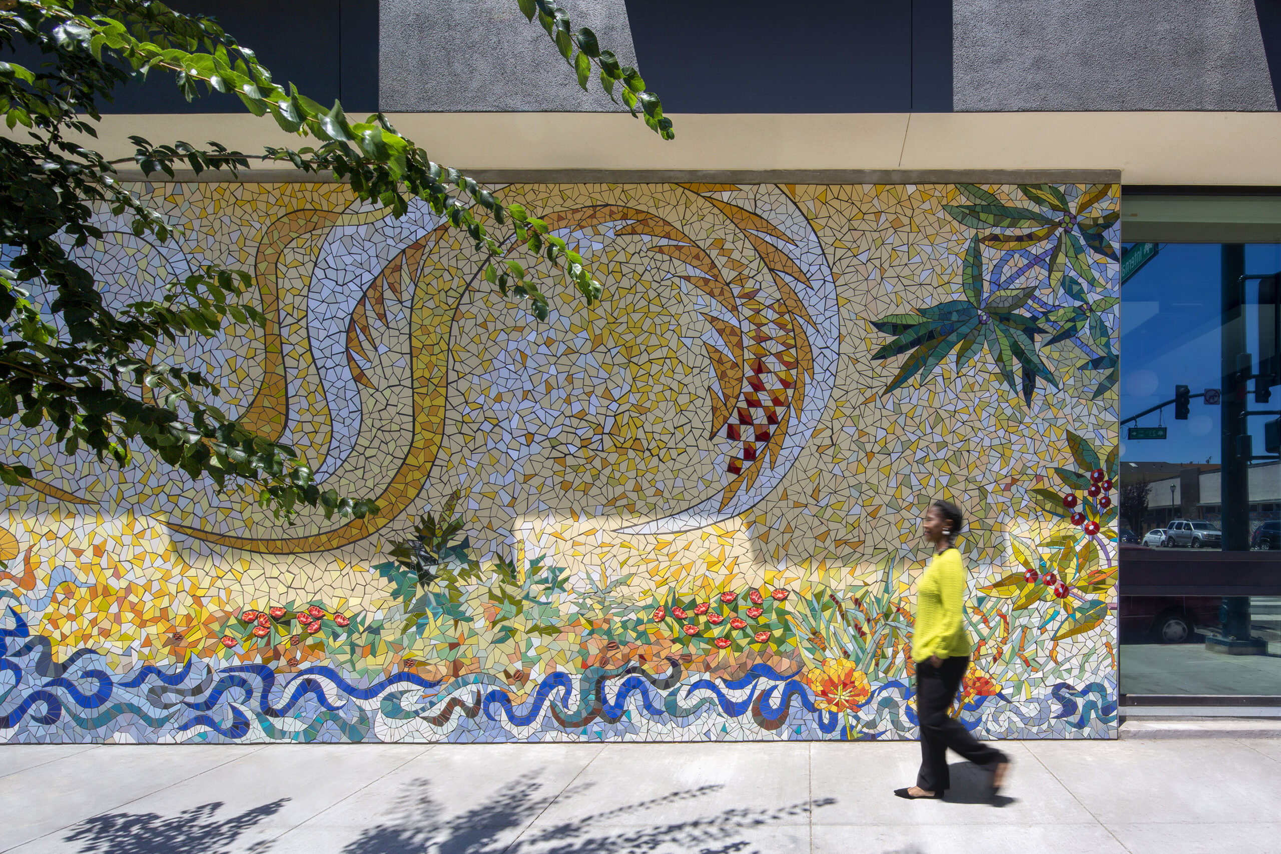 A pedestrian walks past a mosaic mural at Camino 23 in Oakland